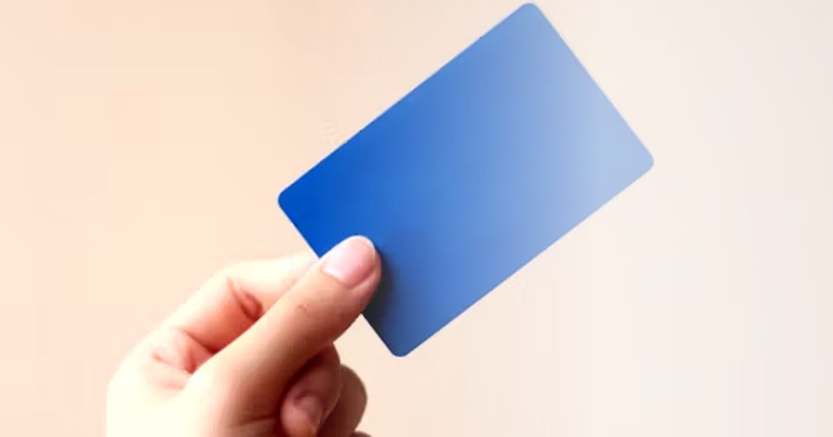 Hand hält eine Kreditkarte vor grauem Hintergrund