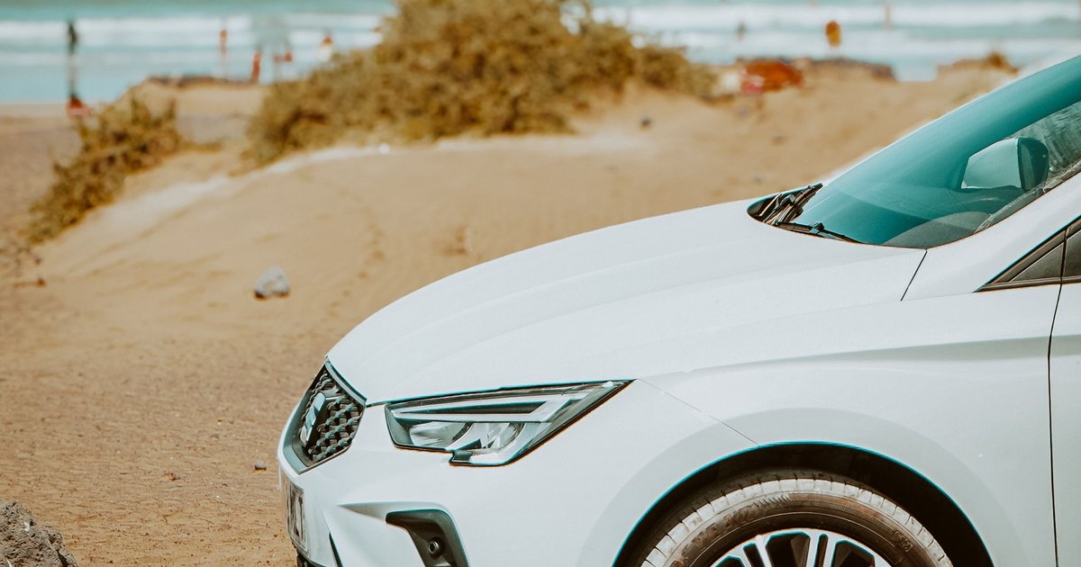 Weißes Mietauto am Strand mit Blick aufs Meer
