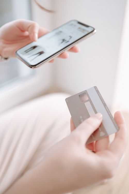Hand hält Smartphone und Bankkarte für die Online-Zahlung eines KI-Abos