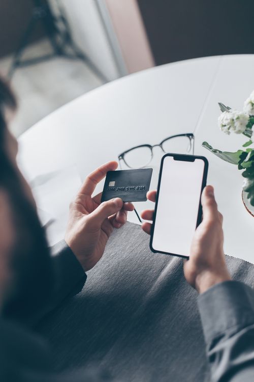 Person nutzt Bankkarte und Smartphone – Umbenennung von Santander zu Openbank