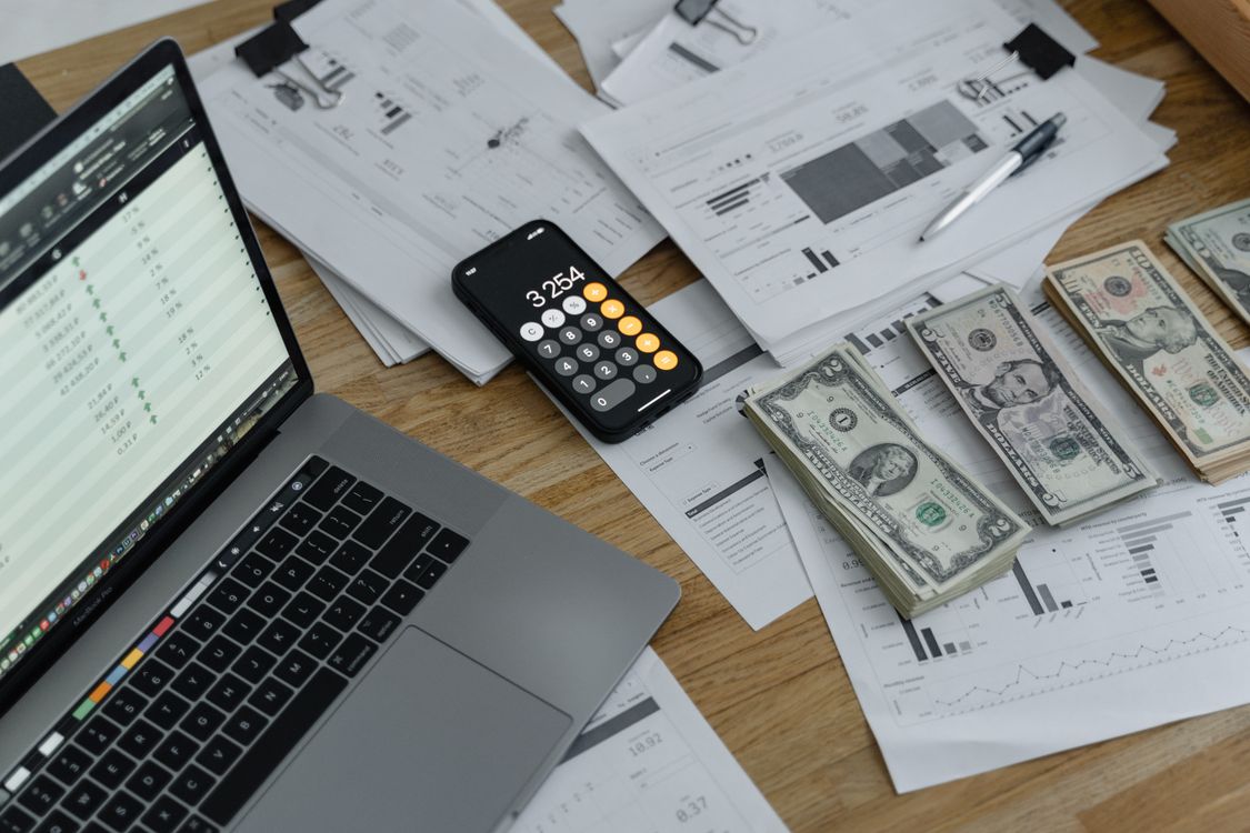 Laptop mit Finanzauswertung und Bargeld als Symbol für Geschäftskonto-Finanzen
