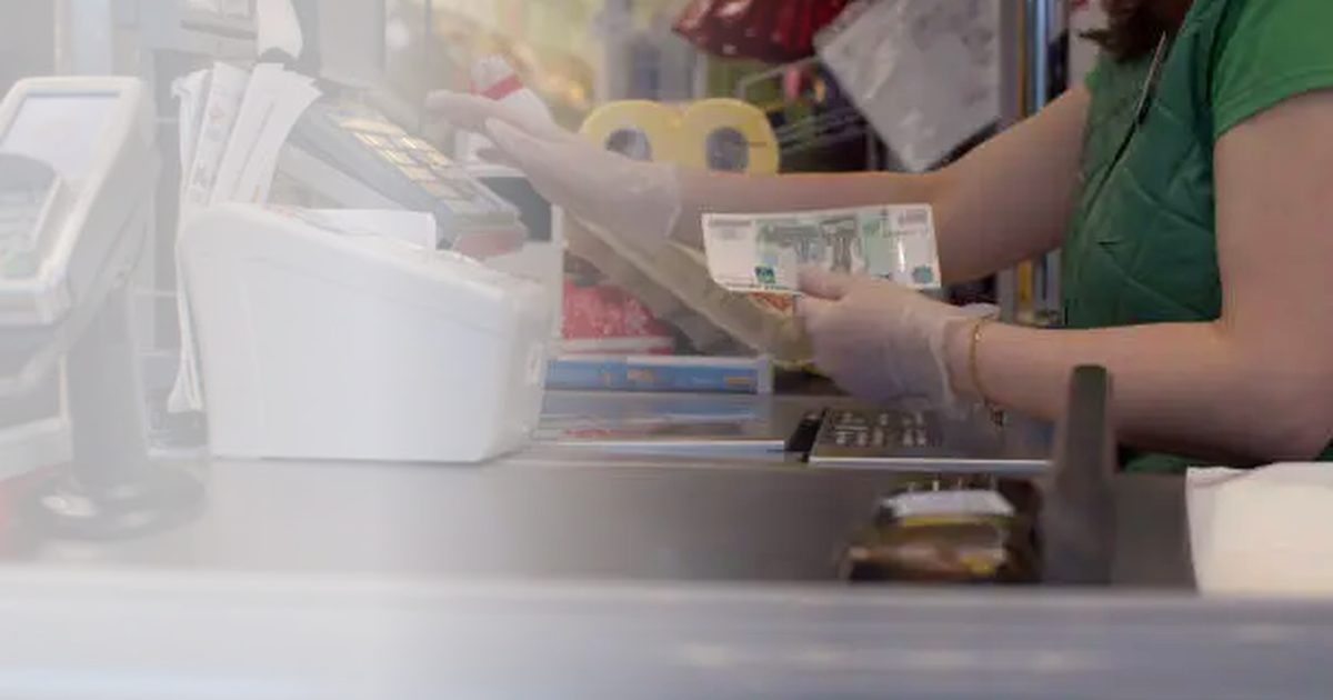 Kassiererin übergibt Bargeld an der Supermarktkasse