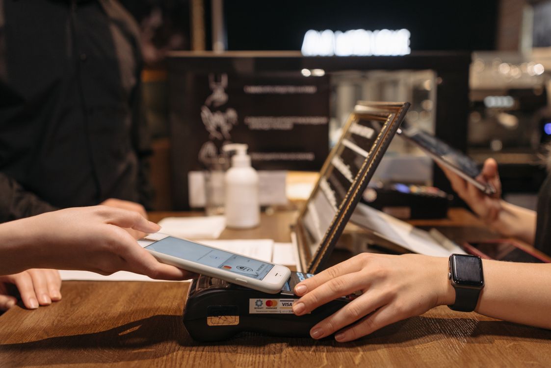 Smartphone wird zum kontaktlosen Bezahlen an ein Kartenterminal gehalten